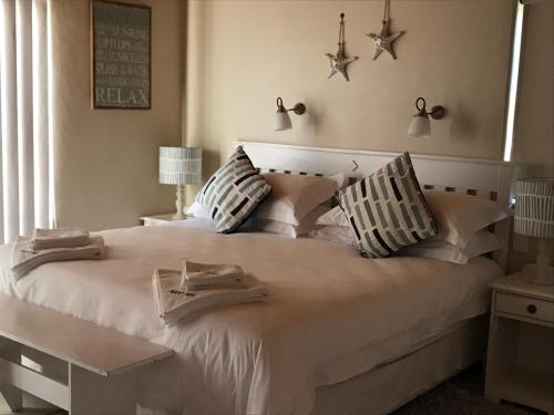 1 dormitorio con 1 cama blanca grande y toallas. en Aan’t See Apartment, en Lambertʼs Bay