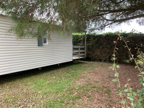 une maison blanche avec terrasse couverte à côté d'un arbre dans l'établissement Camping l’r pur, à Saint-Vincent-sur-Jard