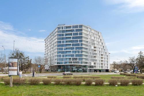 wysoki budynek z samochodem zaparkowanym przed nim w obiekcie Gdańsk Tarasy Bałtyku Sea Side by Downtown Apartments - Sauna, Gym & Parking w Gdańsku