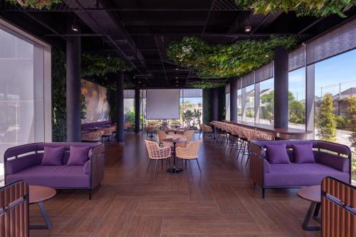 a rendering of a restaurant with purple couches and tables at Grand Mercure Malang in Malang