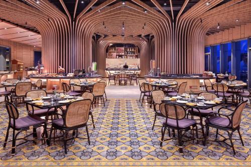 a restaurant with tables and chairs and a bar at Grand Mercure Malang in Malang