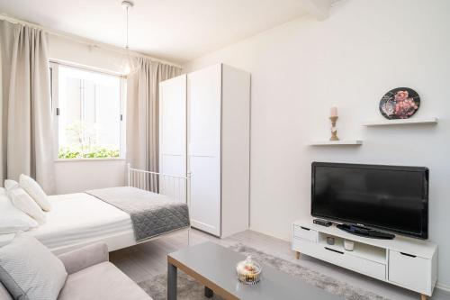 a white living room with a couch and a tv at Apartment Larissa in Dubrovnik
