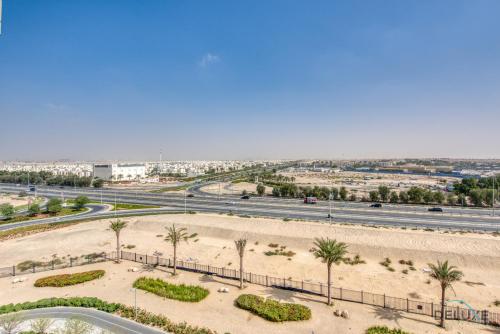 an aerial view of a desert with palm trees and a highway at Fancy 2BR at Hayat Boulevard 2A Town Square By Deluxe Holiday Home in Dubai