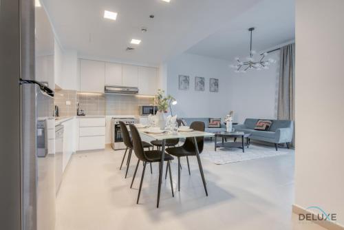 a kitchen and living room with a table and chairs at Fancy 2BR at Hayat Boulevard 2A Town Square By Deluxe Holiday Home in Dubai