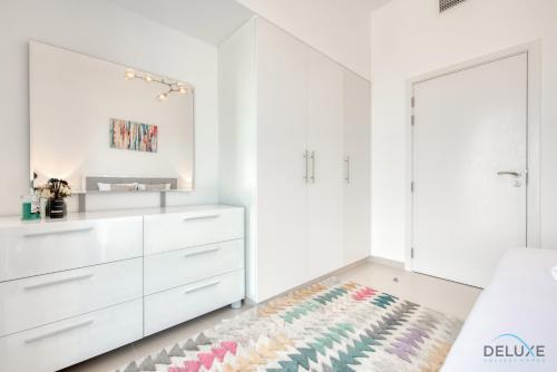 a white bedroom with white cabinets and a rug at Fancy 2BR at Hayat Boulevard 2A Town Square By Deluxe Holiday Home in Dubai