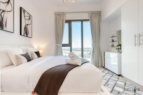 a white bedroom with a large bed and a window at Fancy 2BR at Hayat Boulevard 2A Town Square By Deluxe Holiday Home in Dubai