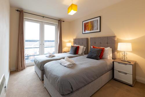 two beds in a bedroom with a large window at BEST PRICE! Superb city centre apartment, 2 Superkings or 4 singles Smart TV & Sofa bed- FREE SECURE PARKING in Southampton