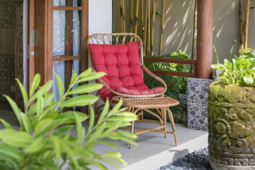 a rattan chair with a red cushion on a porch at Villa SoDe Balangan by Nagisa Bali in Jimbaran