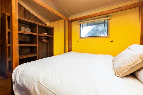 a bedroom with a white bed and a yellow wall at Glamping and Mobile Homes Lavanda - Holiday Centre Bi VIllage in Fažana
