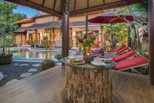 a table on a tree stump next to a pool at Villa SoDe Balangan by Nagisa Bali in Jimbaran