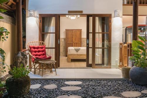 a living room with a red chair and a bedroom at Villa SoDe Balangan by Nagisa Bali in Jimbaran