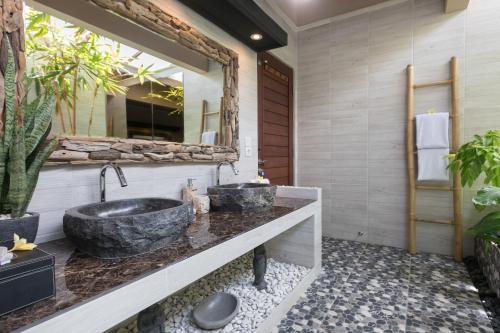 a bathroom with a large stone sink and a mirror at Villa SoDe Balangan by Nagisa Bali in Jimbaran