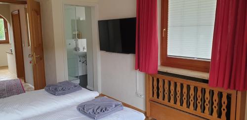 sypialnia z 2 łóżkami, telewizorem i czerwonymi zasłonami w obiekcie Haus Blindauer Eck w mieście Reit im Winkl