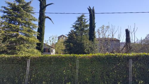 a fence with trees and a house in the background at B&B ABBAZIA Sant'ELENA in Serra San Quirico