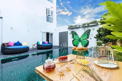 un patio con una mesa con fruta junto a una piscina en H Boutique Hotel Hoi An en Hoi An