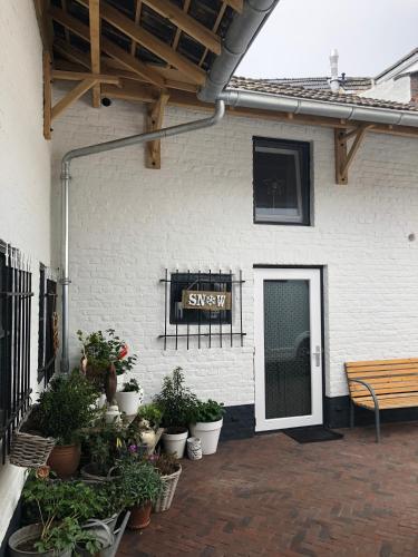 a patio with potted plants and a sign on a building at B&B Emma in Geleen