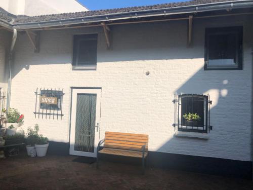 a wooden bench sitting outside of a white building at B&B Emma in Geleen