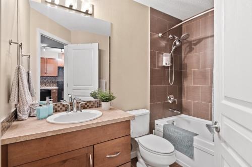 a bathroom with a sink and a toilet and a mirror at Stylish Downtown Condos by GLOBALSTAY in Calgary