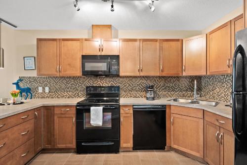 a kitchen with wooden cabinets and black appliances at Stylish Downtown Condos by GLOBALSTAY in Calgary
