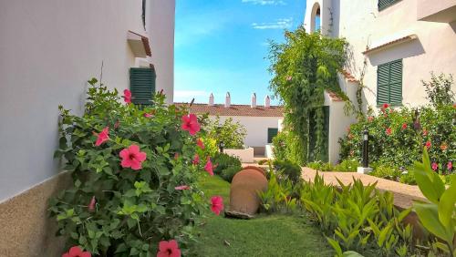 a garden with pink flowers and a building at Ca Minorica -Apartamento- in Son Parc