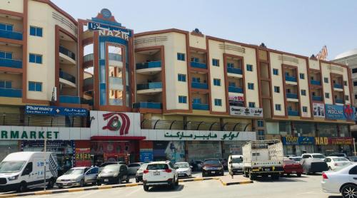a large building with cars parked in a parking lot at FURNISHED BEDROOM APARTMENT IN NAZIR PLAZA in Ajman 