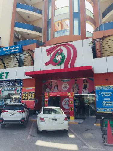 two cars parked in front of a building at FURNISHED BEDROOM APARTMENT IN NAZIR PLAZA in Ajman 