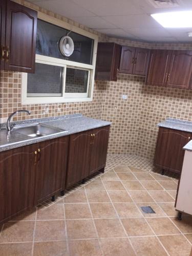 a kitchen with wooden cabinets and a sink at FURNISHED BEDROOM APARTMENT IN NAZIR PLAZA in Ajman 