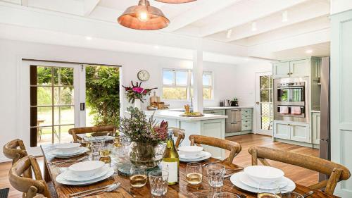 a dining room with a table and chairs and a kitchen at Whisky Creek in Berrima