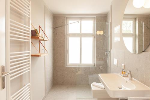 een witte badkamer met een wastafel en een raam bij OSTKÜSTE - Kaiser Karl Design Apartments in Heringsdorf