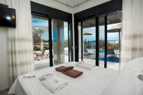 a bedroom with a white bed with a view of a pool at Premium Ionian Villas - Vlachata in Vlachata