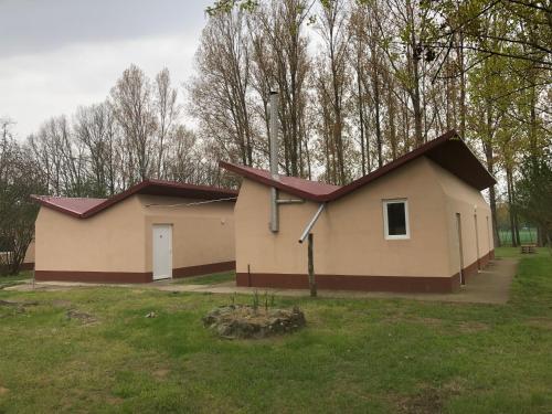 una pequeña casa con techo rojo en un campo en Tóparti Camping en Tiszafüred