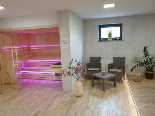 a room with pink lighting and chairs and a bed at Apartamenty Wakacyjne Historie in Międzylesie