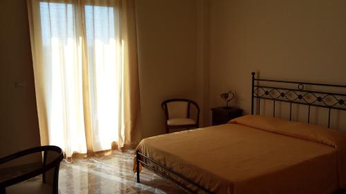 a bedroom with a bed and a window and a chair at B&B Capo Sant'Alessio in SantʼAlessio Siculo