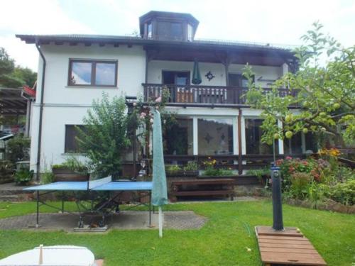 a house with a balcony and a table in the yard at Haus Schipper am Wald in Gemünden