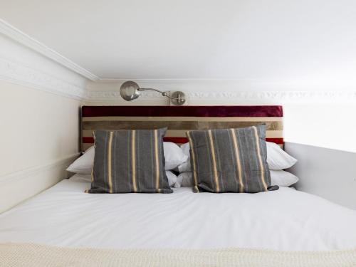 a bedroom with a white bed with two pillows at Pass the Keys Cosy studio flat by Thames river in Chelsea in London