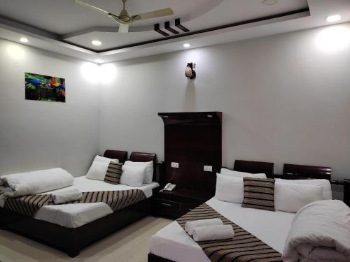 a room with two beds and a ceiling fan at Hotel Krishna Ji in Haridwār