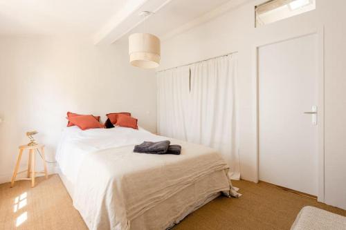 une chambre blanche avec un lit blanc avec des oreillers orange dans l'établissement La Majorquine Arles Arènes, à Arles