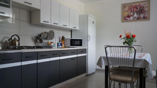 a kitchen with white cabinets and a table with a chair at Groń pokoje w centrum in Brenna