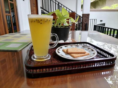 a tray with a glass of beer and a plate of cookies at Ceylonima Home Stay in Anuradhapura