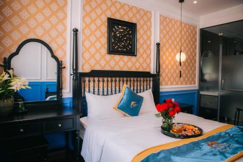 a bedroom with a bed with a vase of flowers on it at Alee Haiphong Hotel in Hai Phong
