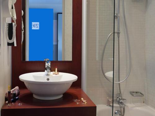 a bathroom with a sink and a shower at Birgit Hôtel Le Havre Centre in Le Havre