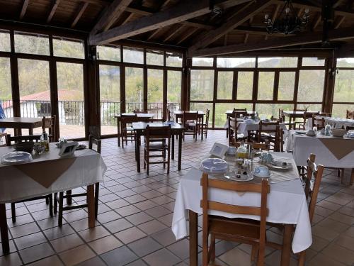 a dining room with tables and chairs and windows at Hotel Avelina in Cangas de Onís