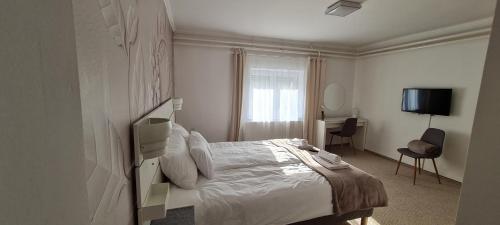ein weißes Schlafzimmer mit einem Bett und einem Schreibtisch in der Unterkunft Lugas Apartman Miskolctapolca 2 hálószoba Dézsa és Jakuzzi közel a Barlangfürdőhöz in Miskolctapolca
