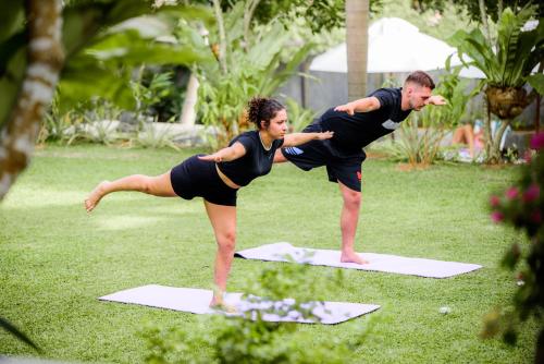 a man and a woman doing yoga on mats at TROPICAL HOUSE - Jungleside Villa in Hikkaduwa