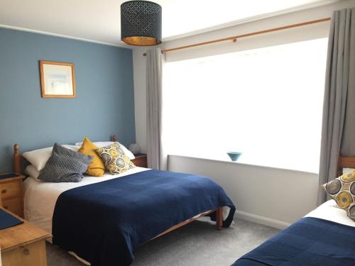 a bedroom with a bed with blue walls and a window at The Seagull, with driveway and patio garden in Whitstable