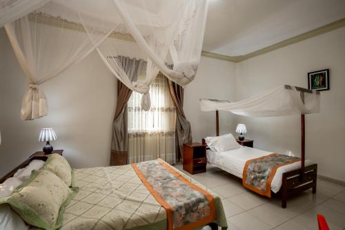 a bedroom with two beds and a window at The Crested Crane Bwindi Hotel in Rugando
