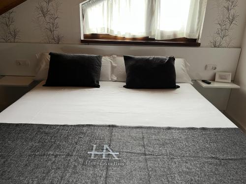 a bed with black pillows in a bedroom at Hotel Avelina in Cangas de Onís