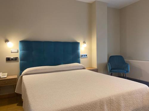 a bedroom with a bed and a blue chair at Hotel Playa de Laxe in Laxe