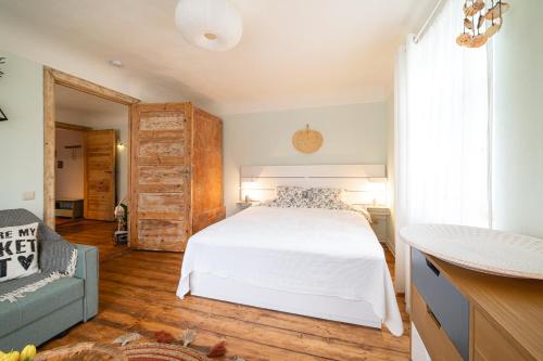 a bedroom with a white bed and a blue couch at Pils Parka Apartamenti in Kuldīga