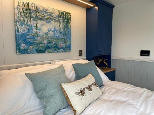 a bed with two pillows on it with a painting at The Bibury - Westwell Downs Shepherd Huts in Oxford